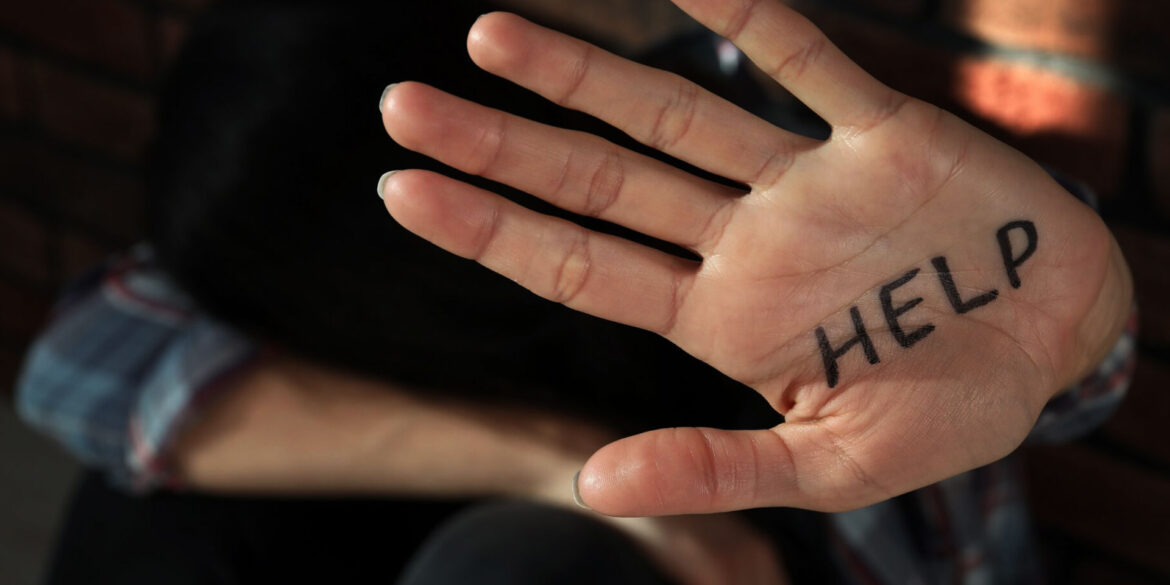 Frau zeigt Hand in die Kamera auf der "Hilfe" steht.