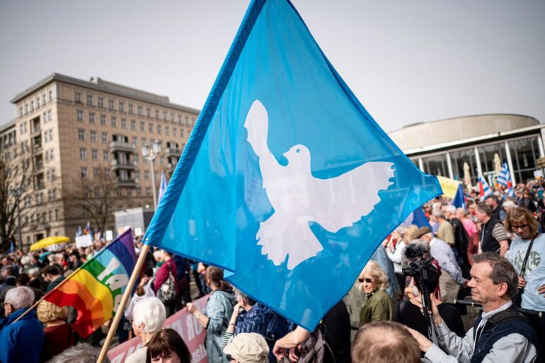Eine Flagge mit der Friedenstaube ist auf dem traditionellen Ostermarsch in Berlin zu sehen.