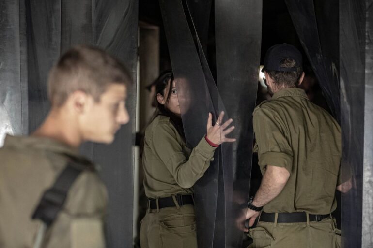 Israelische Soldatinnen und Soldaten besichtigen eine zerstörte Einrichtung im Kibbuz Nir Oz, eine der israelischen Gemeinden, die am 7. Oktober von der Hamas angegriffen wurden.