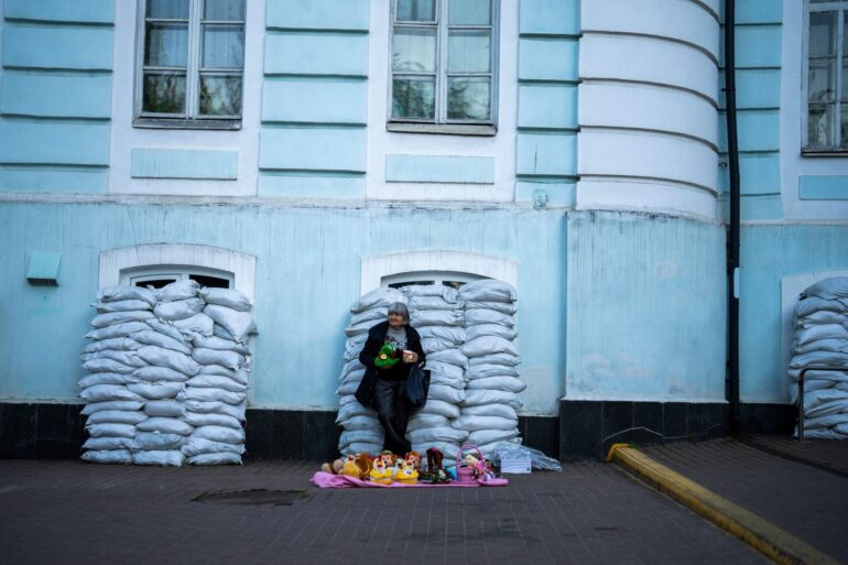 Kiew ist eine Stadt der Gegensätze geworden: Vor mit Sandsäcken geschützten Fenstern verkauft eine Frau Spielzeug. Die Ukraine verteidigt sich nun seit 796 Tagen gegen den russischen Angriffskrieg.