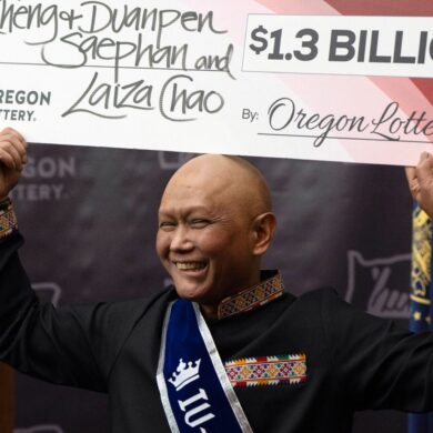 Cheng Saephan hält einen Riesencheck in Höhe von 1,3 Milliarden Dollar in die Höhe.