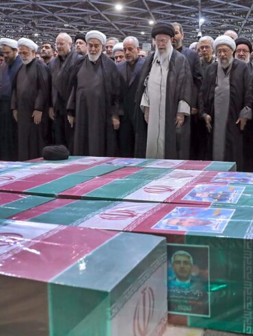 Abschied von Präsident Ebrahim Raisi, Außenminister Hussein Amirabdollahian und den weiteren beim Hubschrauberabsturz Getöteten: Irans Religionsführer Ajatollah Ali Chamenei (M.r.) spricht in Teheran an den mit Flaggen bedeckten Särgen ein Gebet.
