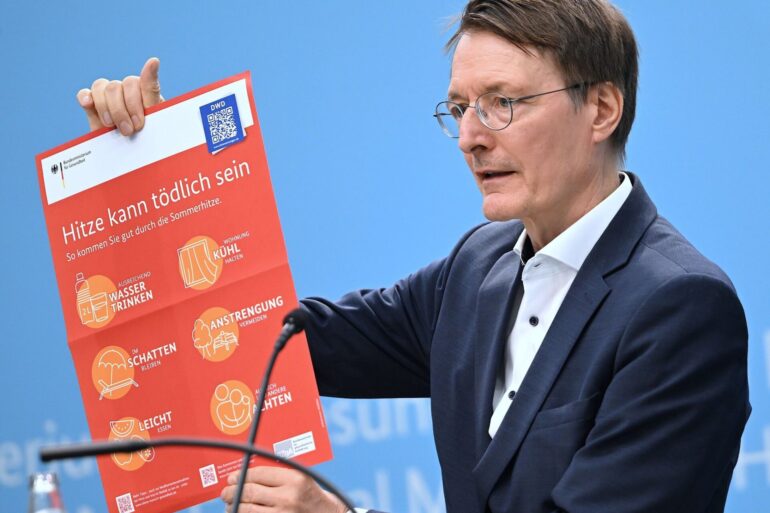 Bundesgesundheitsminister Karl Lauterbach (SPD) hält ein Plakat zum Thema Hitzeschutz hoch.