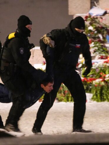Polizeibeamte halten einen Mann fest, der Blumen zu Ehren von Alexej Nawalny an einem Denkmal für die Opfer der sowjetischen Unterdrückung in St. Petersburg niedergelegt hat.