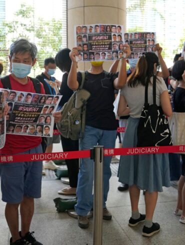 Unterstützer halten vor einem Gericht in Hongkong Plakate mit den Fotos einiger der 47 angeklagten Demokratie-Aktivisten in die Höhe.