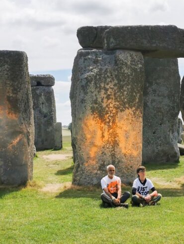 Demonstranten von «Just Stop Oil» sitzen vor dem Steinmonument Stonehenge, das sie zuvor mit orangener Farbe besprüht haben.