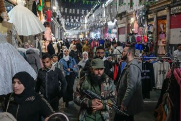Ein Oppositionskämpfer geht zwischen Kunden in Damaskus über den Markt