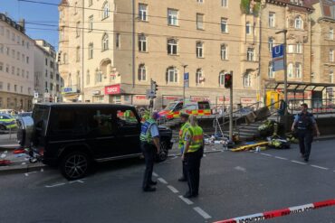Am frühen Abend fährt ein Fahrzeug in eine Menschengruppe an einer Bahnhaltestelle.