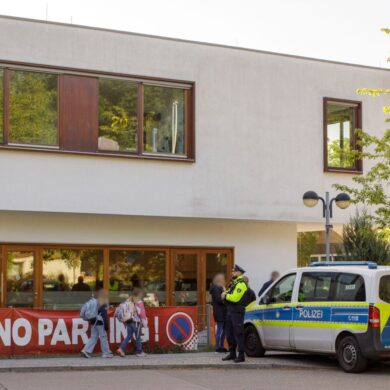Die Polizei steht vor einer Grundschule im Berliner Bezirk Spandau, während Schüler am Morgen zur Schule kommen.
