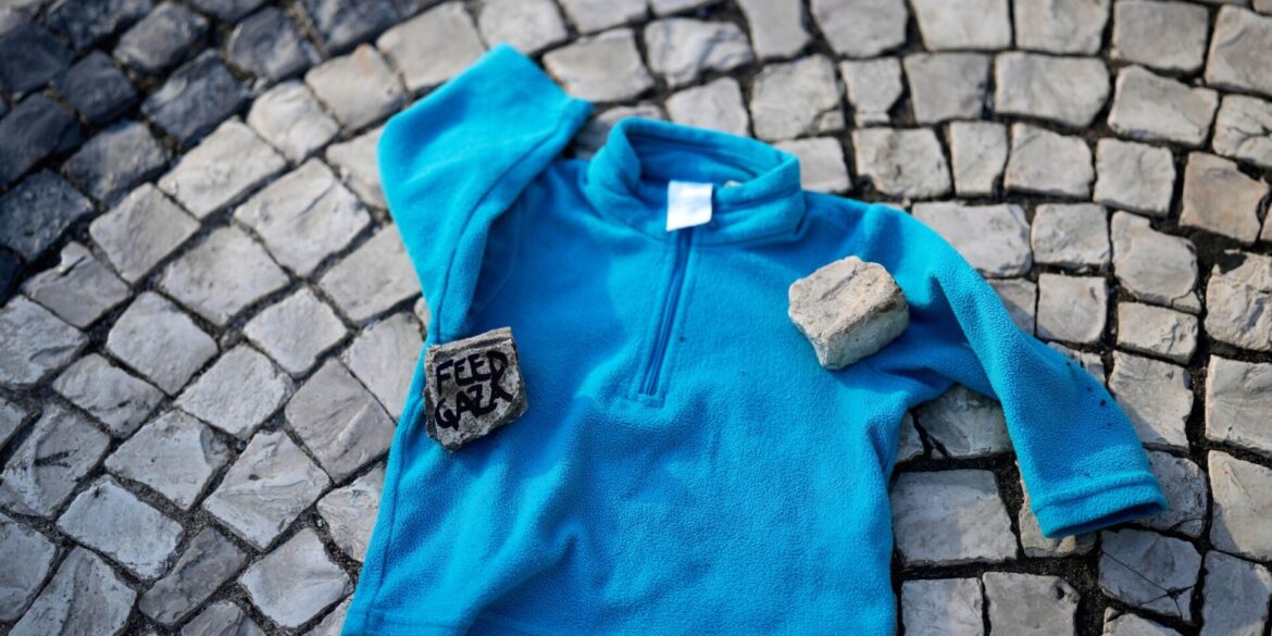 Bei einer Demonstration gegen den Krieg in Gaza liegt Kinderkleidung neben Listen von im Gazastreifen getöteten palästinensischen Kindern auf dem Boden in der Innenstadt von Lissabon.