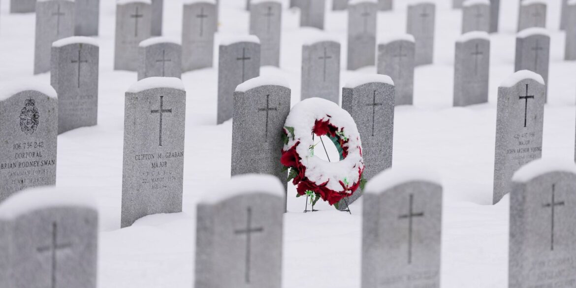 Ein schneebedeckter Kranz lehnt an einem Grabstein vor der Gedenkfeier zum Remembrance Day auf dem nationalen Soldatenfriedhof in Beachwood in Ottawa in Kanada.