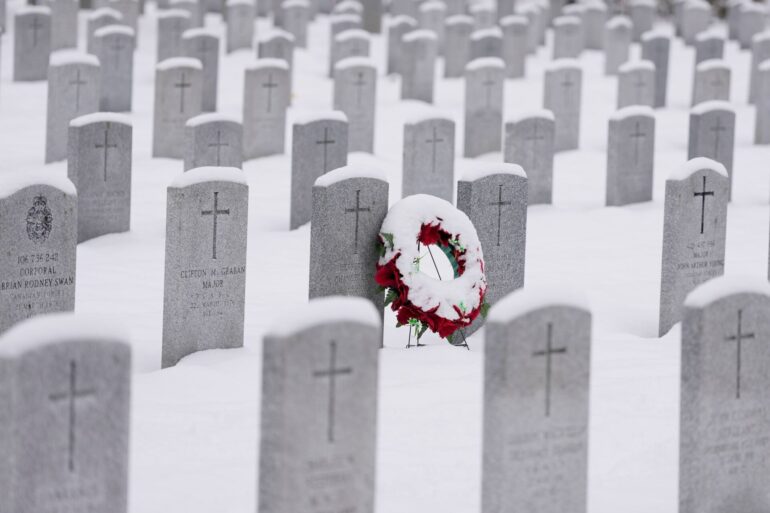 Ein schneebedeckter Kranz lehnt an einem Grabstein vor der Gedenkfeier zum Remembrance Day auf dem nationalen Soldatenfriedhof in Beachwood in Ottawa in Kanada.