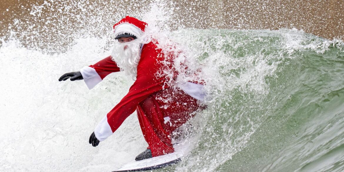 Surflehrer und Rettungsschwimmer Finn Clark aus Gorebridge verkleidet sich als Weihnachtsmann für eine Surfsession im Lost Shore Surf Resort in Newbridge, in der Nähe von Edinburgh.