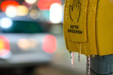 Ein vereister Tastschalter ist an einer Haltestelle in Brandenburg am frühen Morgen zu sehen.