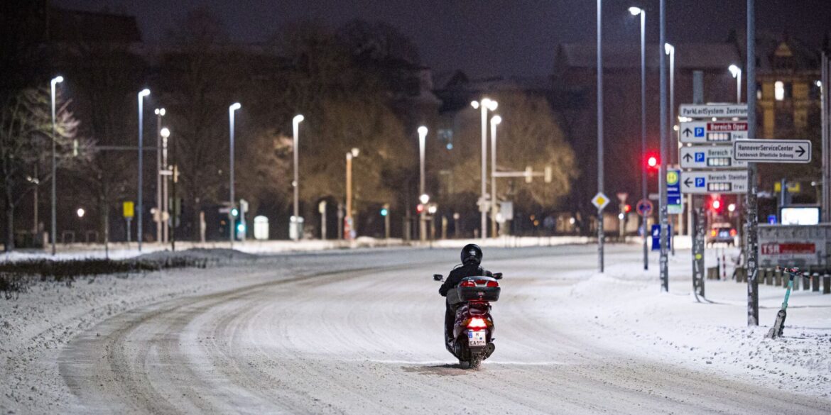 Motorroller kämpft sich am frühen Morgen durch Schnee im Stadtzentrum in Hannover