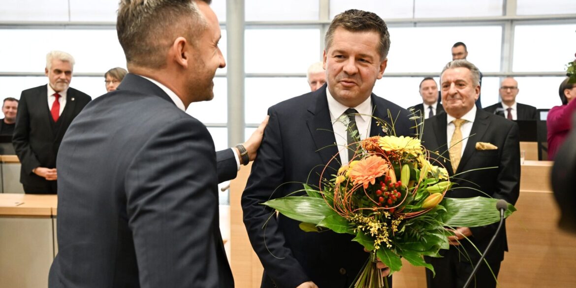 Sven Schulze bekommt Glückwünsche und einen Blumenstrauß vom AfD-Spitzenkandidaten Ulrich Siegmund.