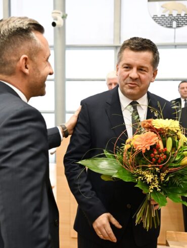 Sven Schulze bekommt Glückwünsche und einen Blumenstrauß vom AfD-Spitzenkandidaten Ulrich Siegmund.