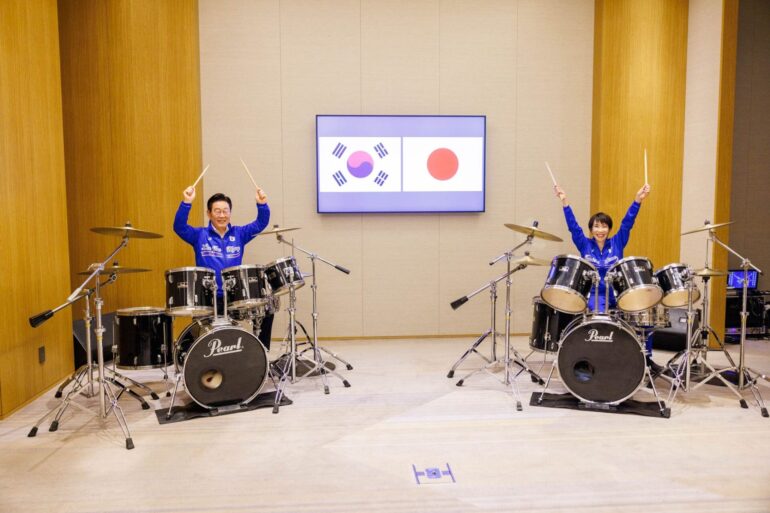 Die japanische Ministerpräsidentin Sanae Takaichi (r) und der südkoreanische Präsident Lee Jae Myung spielen Schlagzeug.