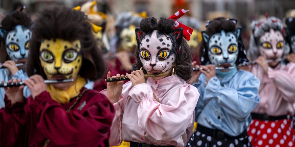 Teilnehmer mit Katzenmasken ziehen beim Fasnachts-Umzug in Basel durch die Straßen.