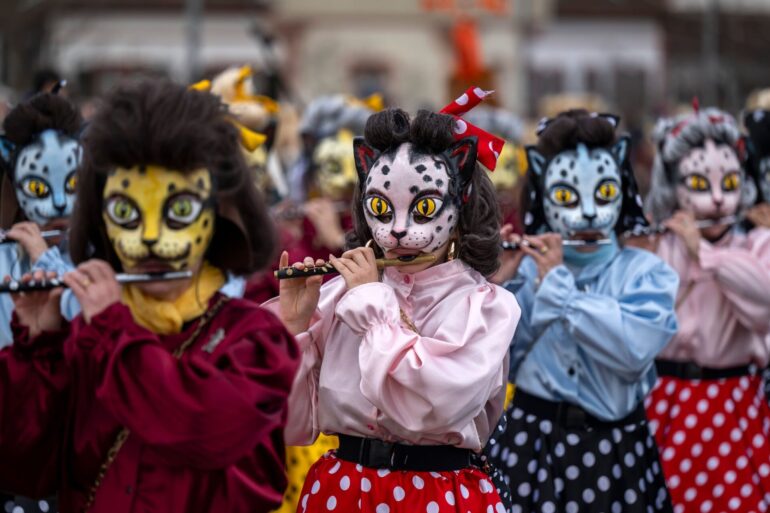 Teilnehmer mit Katzenmasken ziehen beim Fasnachts-Umzug in Basel durch die Straßen.