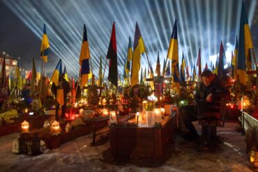 Flutlichter leuchten in Lwiw über den Gräbern der gefallener Soldaten, während Menschen am Vorabend des vierten Jahrestages der russischen Invasion Kerzen anzünden.