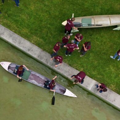 Studenten und Studentinnen der Bauhaus-Universität Weimar fahren mit dem Betonkanu auf dem Wasser im Weimarer Schwanseebad. (Aufnahme mit einer Drohne)