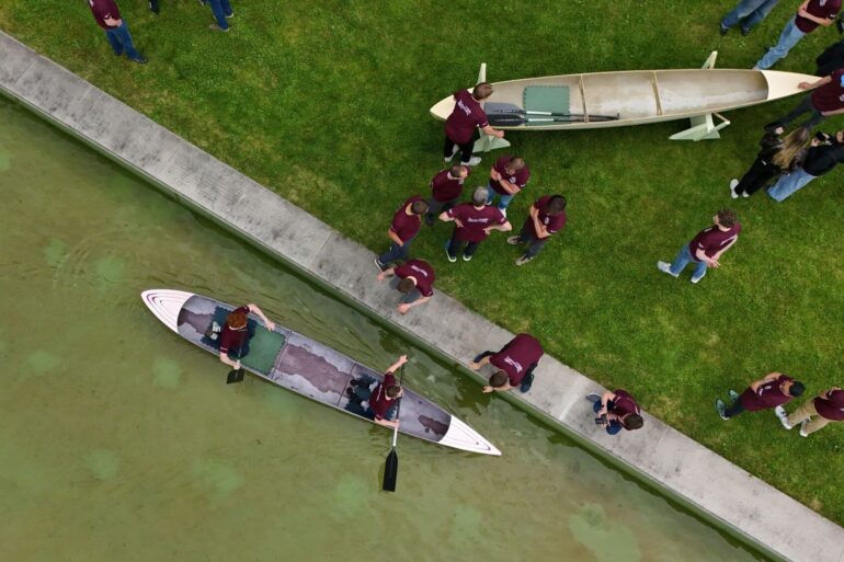 Studenten und Studentinnen der Bauhaus-Universität Weimar fahren mit dem Betonkanu auf dem Wasser im Weimarer Schwanseebad. (Aufnahme mit einer Drohne)
