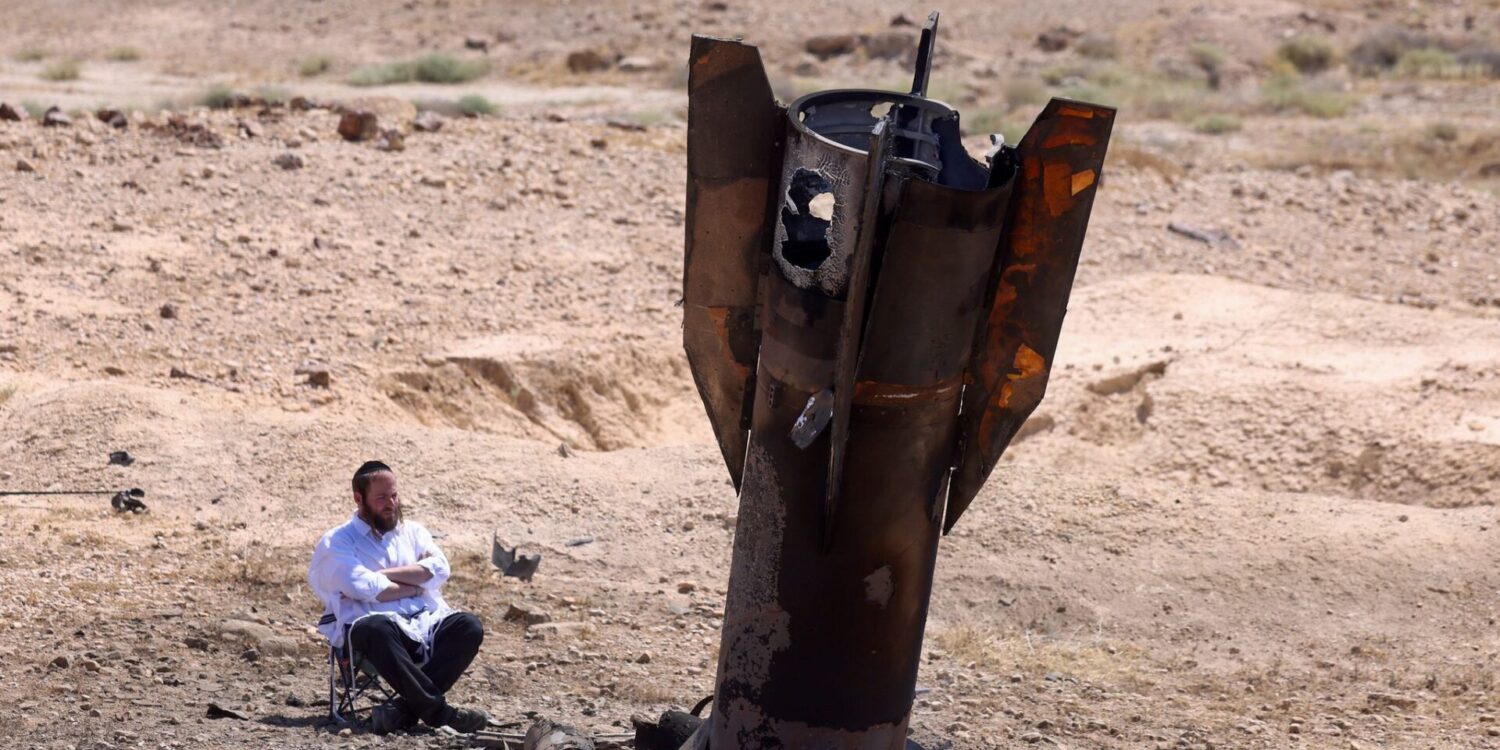 Ein Mann betrachtet das Wrack einer Rakete, die nach einem iranischen Angriff im Westjordanland aus dem Boden ragt.