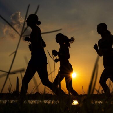 Menschen joggen am Potomac River entlang, während die Sonne in der Nähe des Washington Monument aufgeht.