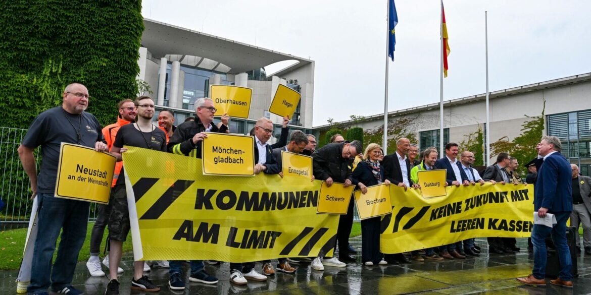 Vertreter mehrerer Städte und Kommunen demonstrieren mit Schildern und Bannern für finanzielle Unterstützung in Berlin.