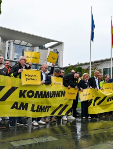 Vertreter mehrerer Städte und Kommunen demonstrieren mit Schildern und Bannern für finanzielle Unterstützung in Berlin.