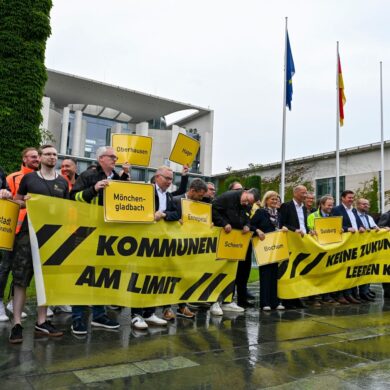Vertreter mehrerer Städte und Kommunen demonstrieren mit Schildern und Bannern für finanzielle Unterstützung in Berlin.