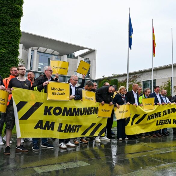 Vertreter mehrerer Städte und Kommunen demonstrieren mit Schildern und Bannern für finanzielle Unterstützung in Berlin.