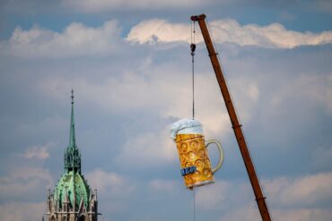 Ein übergroßer und rund 1,5 Tonnen schwerer Bierkrug wird mit einem Kran auf der Theresienwiese an seinen Platz gehoben. Das 191. Oktoberfest beginnt dieses Jahr am 19. September 2026 und endet am 04. Oktober 2026.