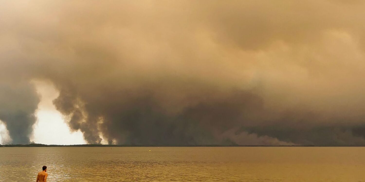 Strandbesuch vor Rauchwolken in Lacanau im Südwesten Frankreichs.
