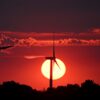 Hinter Windrädern färbt die sinkende Sonne den Himmel über Nordrhein-Westfalen rot.