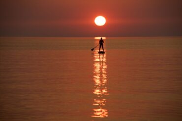 Ein Urlauber steuert bei Sonnenuntergang vor der Küste von Jantarny dem früheren ostpreußischen Palmnicken, einem Ferienort in der westrussischen Region Kaliningrad, ein Stand-up-Paddleboard.