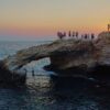 Ein junger Mann springt bei Sonnenuntergang im Ferienort Ayia Napa auf der im östlichen Mittelmeer gelegenen Insel Zypern von der natürlichen "Liebesbrücke" ins Meer.
