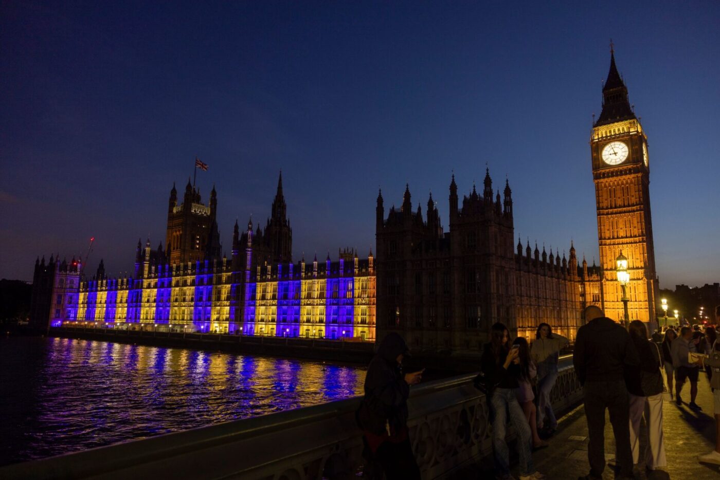 Der Westminster-Palast in London ist blau-gelb beleuchtet.