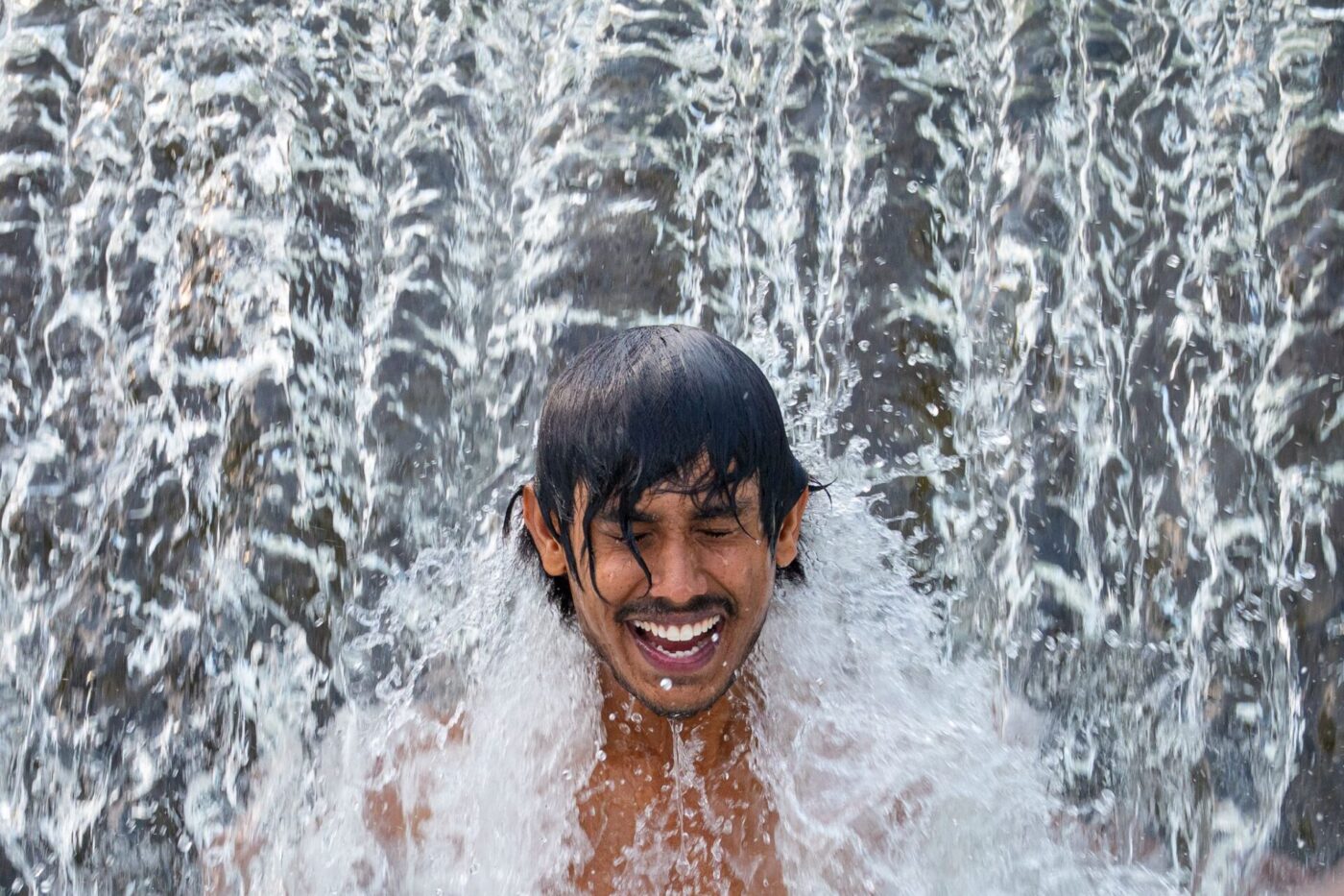 Ein Gastarbeiter aus Sri Lanka kühlt sich an einem glühend heißen Tag in einer Wasserkaskade eines Flusses außerhalb der Stadt Bragadiru in Rumänien ab.