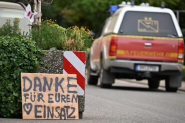 Ein Fahrzeug der Feuerwehr fährt an einem Schild mit der Aufschrift "Danke für Euren Einsatz" beim Waldbrand im Hürtgenwald vorbei.