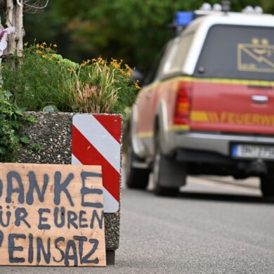 Ein Fahrzeug der Feuerwehr fährt an einem Schild mit der Aufschrift "Danke für Euren Einsatz" beim Waldbrand im Hürtgenwald vorbei.