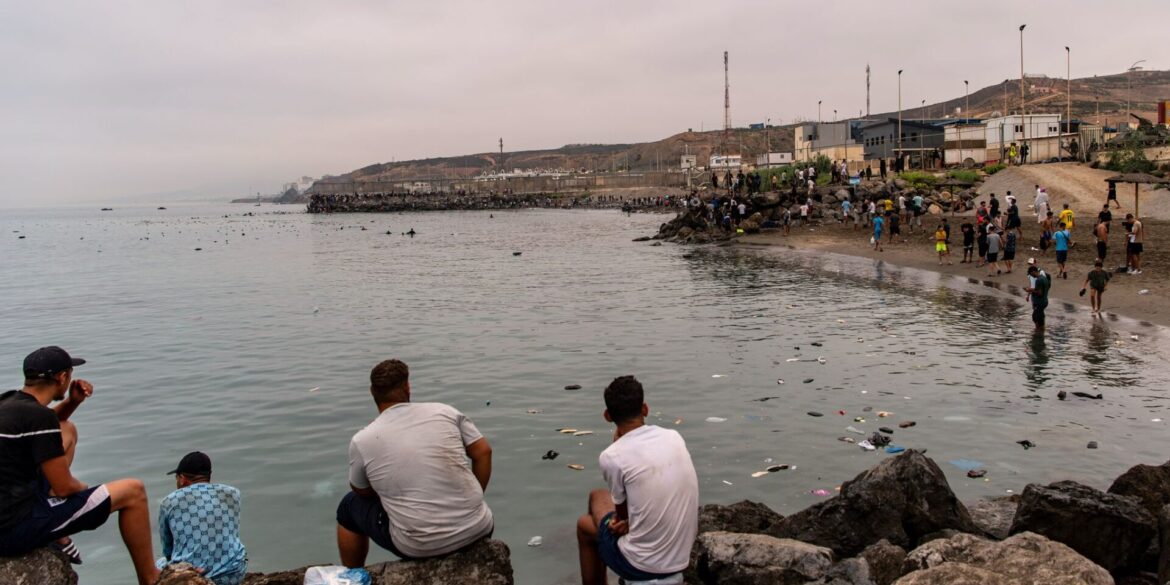 Migranten blickten von Felsen aus, während andere aus der spanischen Enklave Ceuta nach Marokko zurückkehrten.