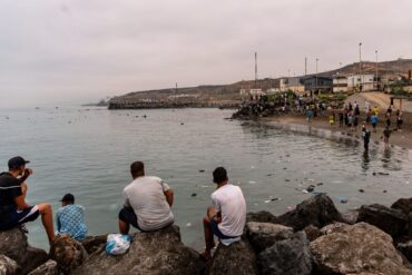 Migranten blickten von Felsen aus, während andere aus der spanischen Enklave Ceuta nach Marokko zurückkehrten.