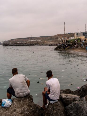 Migranten blickten von Felsen aus, während andere aus der spanischen Enklave Ceuta nach Marokko zurückkehrten.