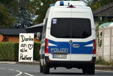 Ein Polizeifahrzeug fährt an einem Schild mit der Aufschrift «Danke an alle Helfer» vorbei.