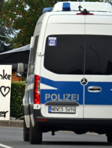 Ein Polizeifahrzeug fährt an einem Schild mit der Aufschrift «Danke an alle Helfer» vorbei.