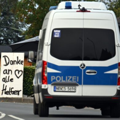 Ein Polizeifahrzeug fährt an einem Schild mit der Aufschrift «Danke an alle Helfer» vorbei.