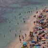 Menschen sonnen sich und entspannen am Meer am Strand von Caleta de Portals Nous auf Mallorca.