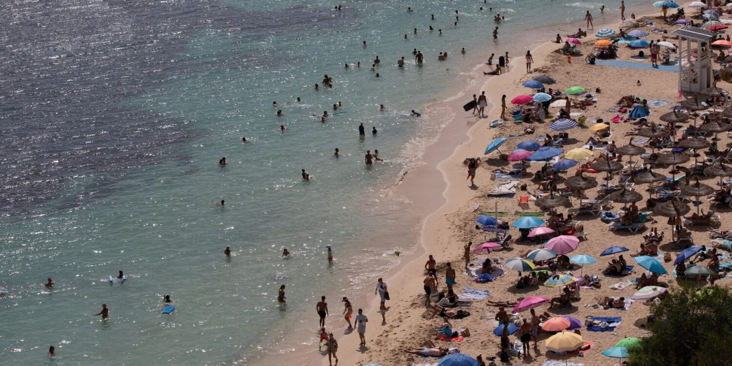 Menschen sonnen sich und entspannen am Meer am Strand von Caleta de Portals Nous auf Mallorca.